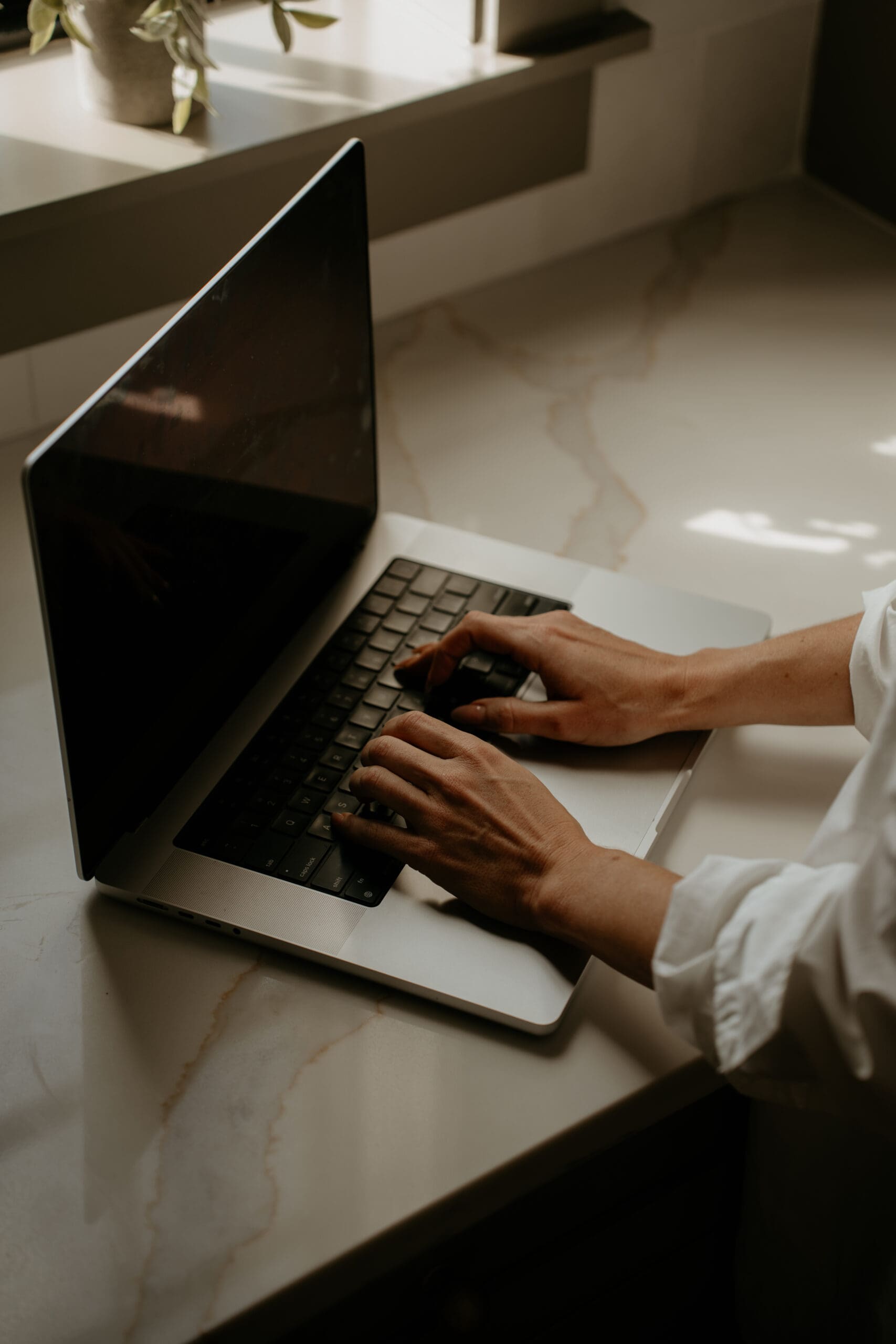 woman typing on comptuer in kitchen